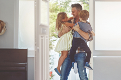Shot of a father embracing his two children as he enters the house